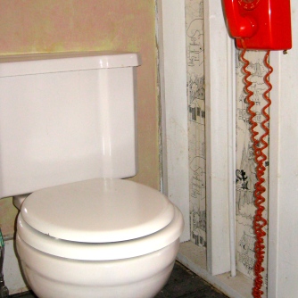 Orange phone hanging by the toilet